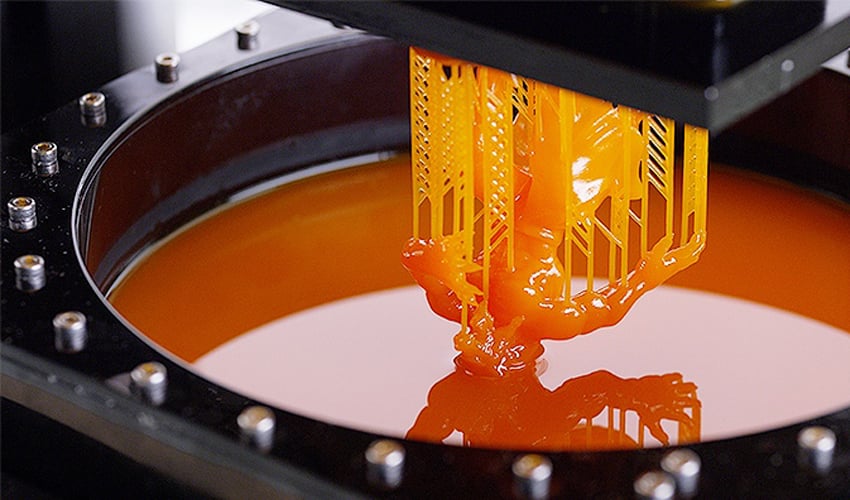 An SLA print rises from the resin. 
