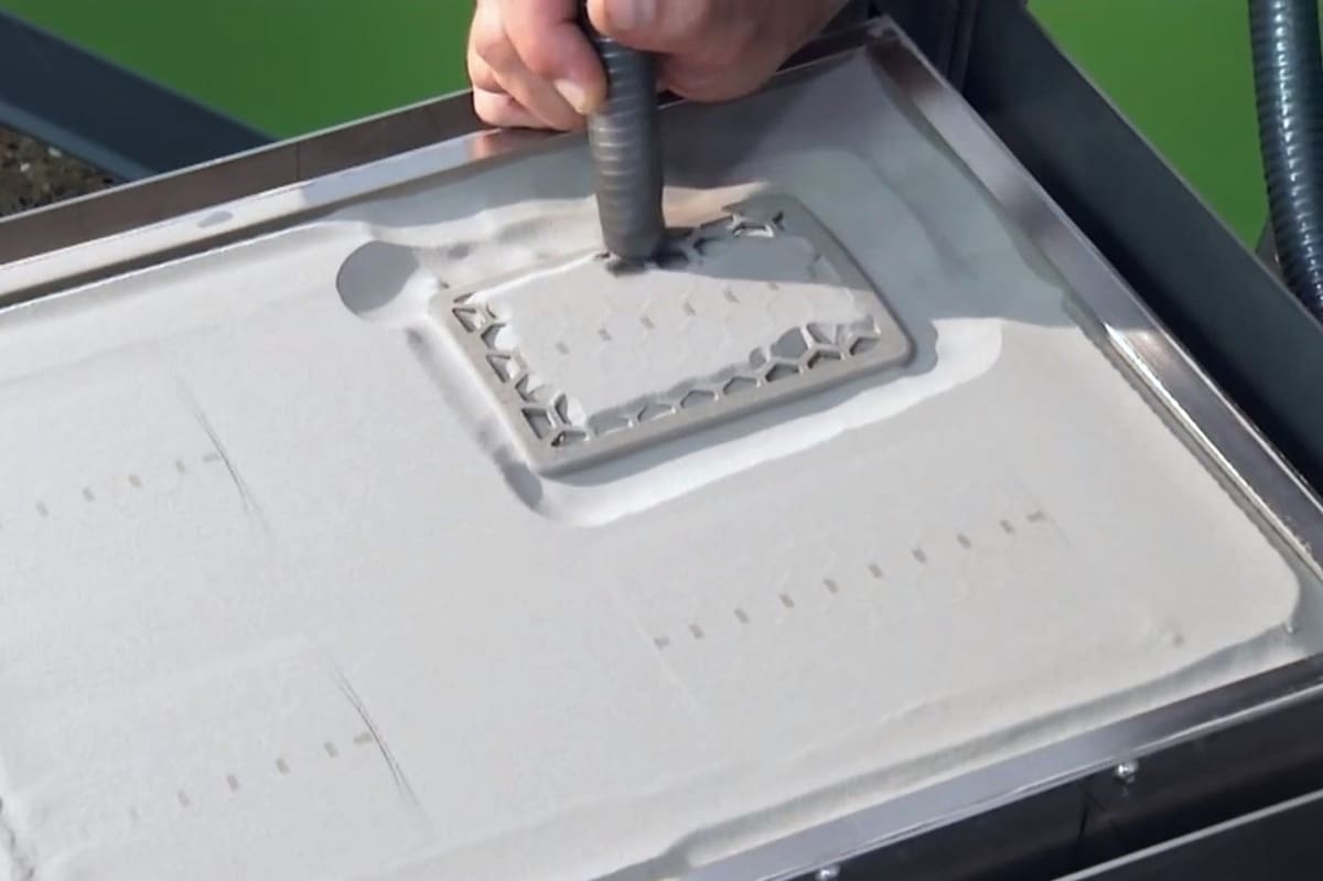 Removing the excess powder from a binder jet print.