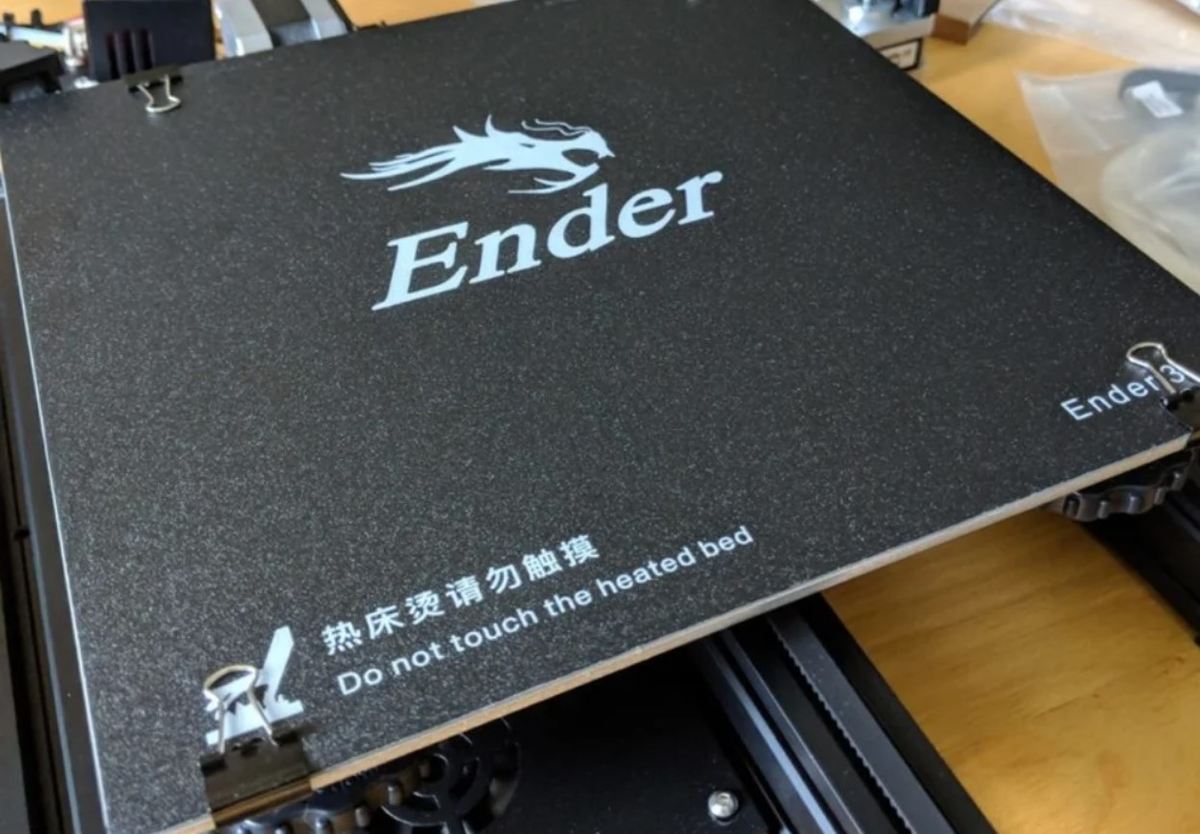 An Ender 3 print bed with the factory binder clips