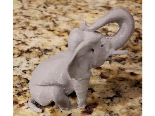 A sitting adult elephant with arched trunk.