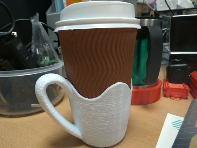 This cup holder has an integrated handle, bringing the convenience of a mug to cheaper paper cups