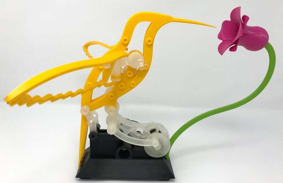 The hummingbird dips its long beak into the attached flower