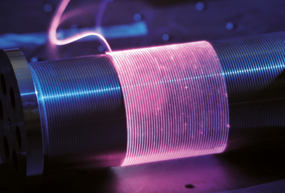 Coiling an optical fiber laser allows for a longer length of fiber cable with substantial increase in power without any increase in size
