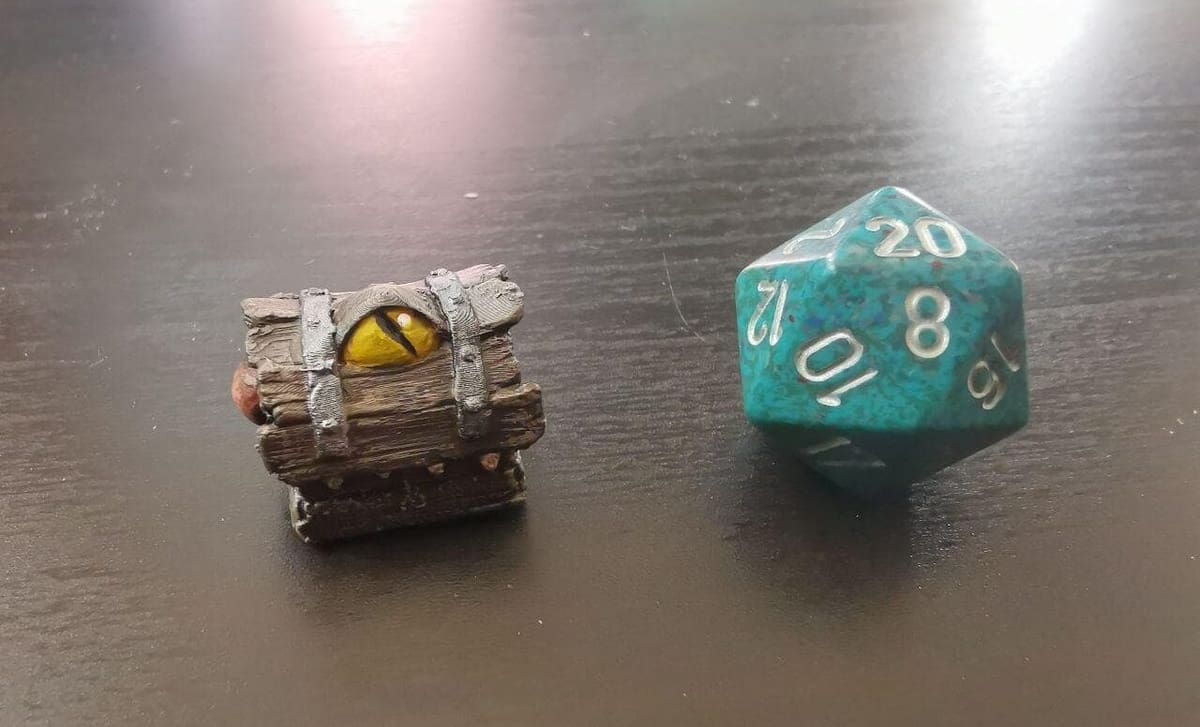 An adorable mimic next to a D20 for scale